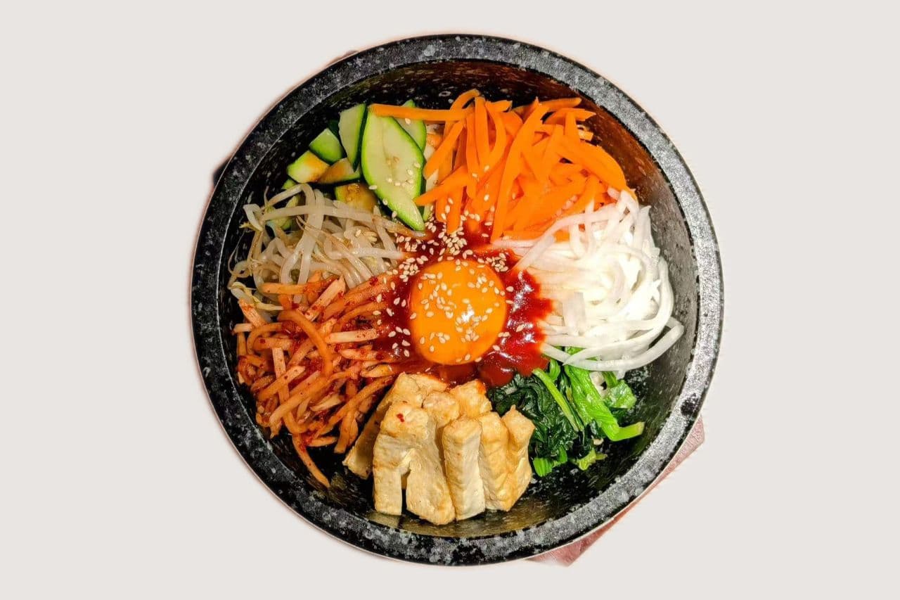 Vegetarisches Dolsot Bibimbap mit Gemüse und Ei im heißen Steintopf