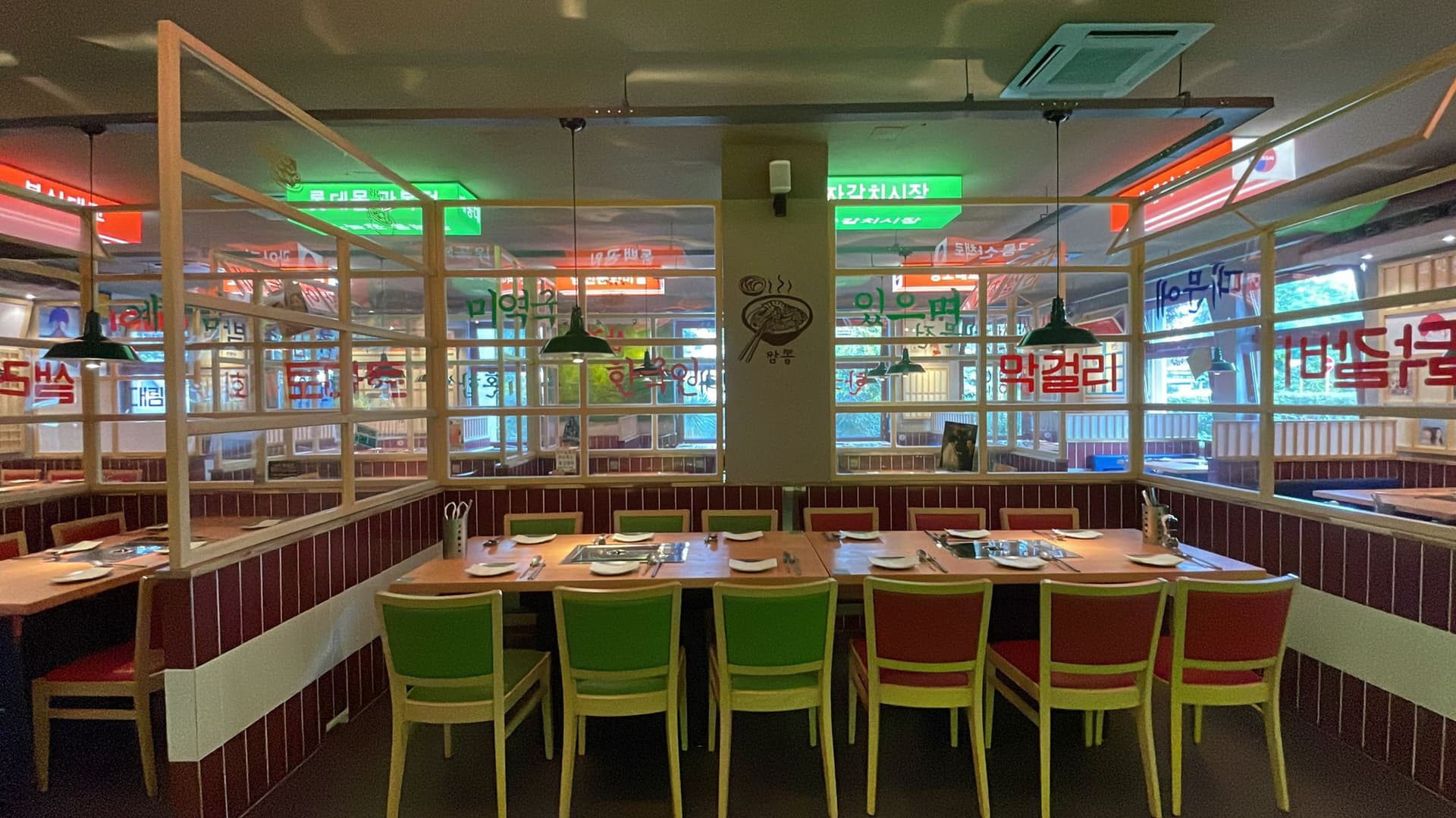 Der Gastraum von NEW ASIA BBQ mit Tischgrills, Holztischen und koreanischen Schildern